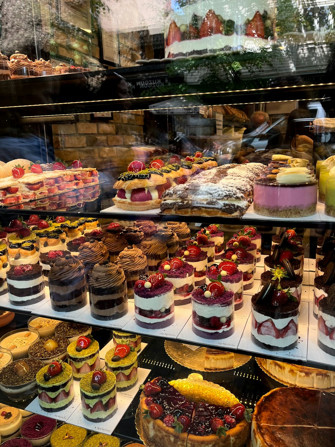Assorted cakes and pastries sit inside a glass bakery case.