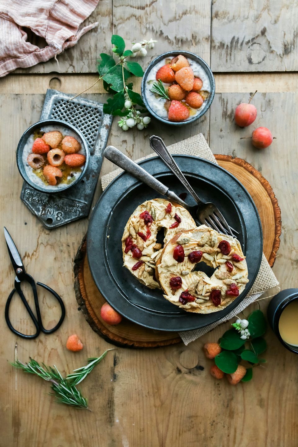 Overhead view of a breakfast spread with bagels and yogurt on a wooden table.
