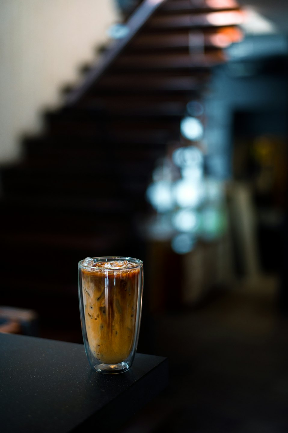 Layered iced coffee sits on a dark textured counter.