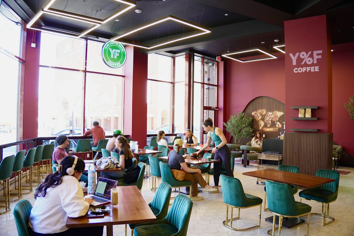 Customers work and socialize at wooden tables in a cafe.