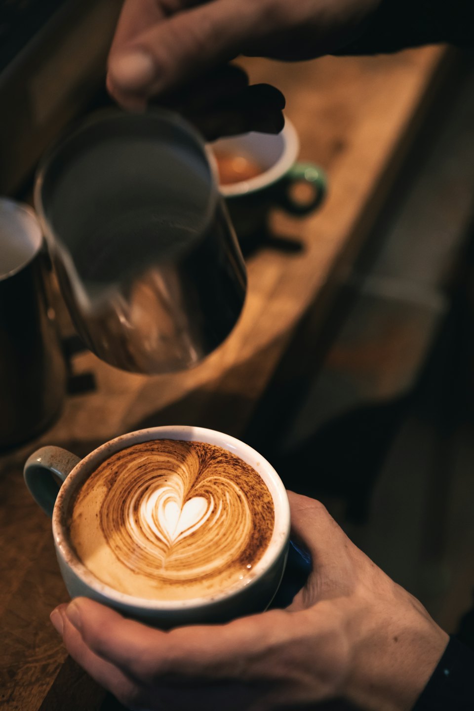 A barista pours steamed milk into a coffee cup.